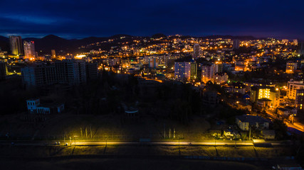 Drone view of the seaside with the illuminated district of the city of Sochi at dusk, Russia
