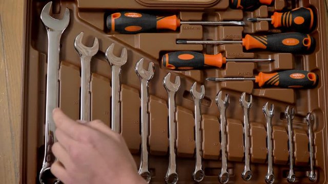 Girl is choosing between spanners in toolbox and taking one, repairing conception, top shot