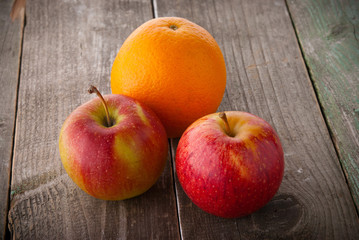 Apples and an orange on a wooden background