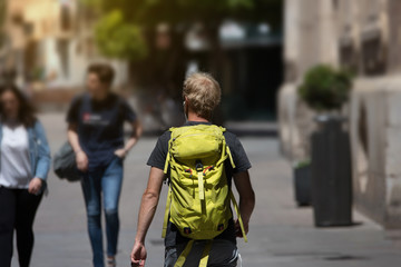 Fototapeta premium Man alone backpacker traveling round the world with his green backpack passing through the city