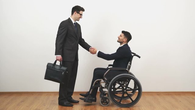 The disabled and a businessman handshake on the white wall background