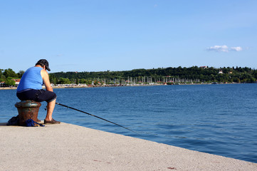 pécheur assis sur une bitte d’amarrage, portoroz, slovenie  