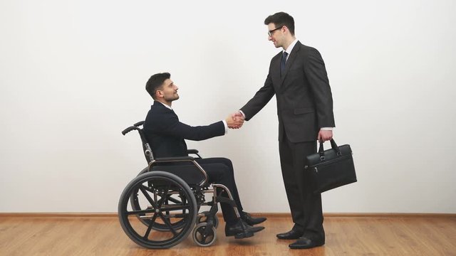 The disabled and a businessman handshake on the white wall background