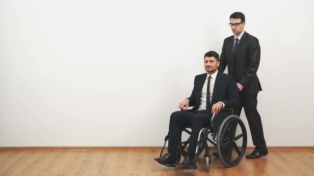The businessman walking with a disabled on a wheelchair on the white background