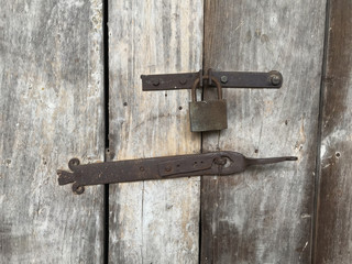 Vintage lock and antique latch on a rustic wooden textured door of an old country farmhouse - concept for keeping a secret
