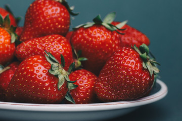 Close up red fresh strawberries on a plate isolated on grey background