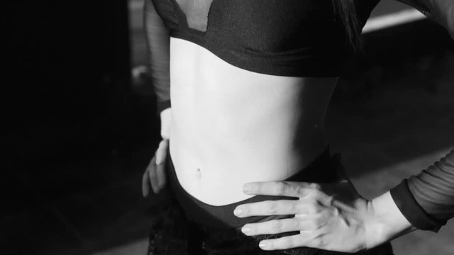 Closeup woman's body and legs standing close to the window with lace curtain pattern shadow and sun rays - black and white video in slow motion