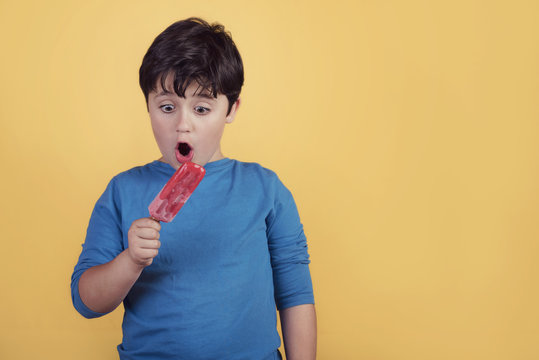 niño con un helado de fresa sobre fondo amarillo
