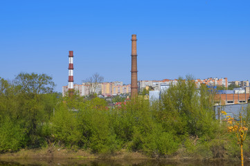 Fototapeta na wymiar Industrial landscape with factory pipes against the blue sky and