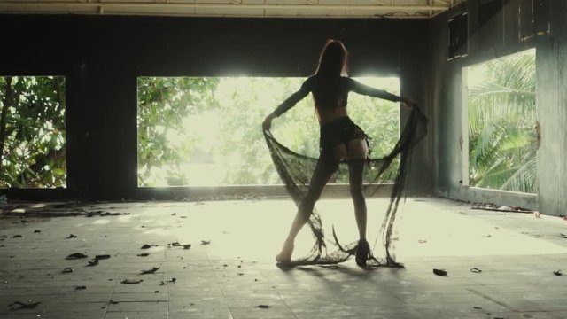 Beautiful woman playing with lace fabric. Sensual girl dancing in abandoned building - video in slow motion