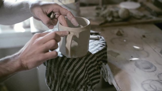 Closeup potter join handle to cup on potter wheel