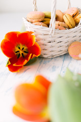 Blossoming tulips with macaroons on a light wooden background. Still life, spring concept