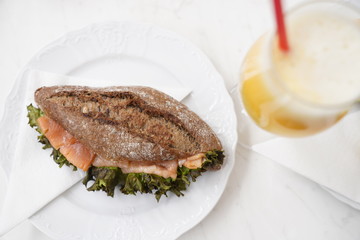 Bread with salmon fish and fresh orange juice in a glass for breakfast on a white table