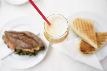 Bread with salmon fish and fresh orange juice in a glass for breakfast on a white table