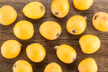 Fresh orange Japanese loquats flatlay isolated on brown wood background.