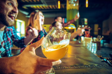Sport, people, leisure, friendship and entertainment concept - happy football fans or male friends drinking beer and celebrating victory at bar or pub