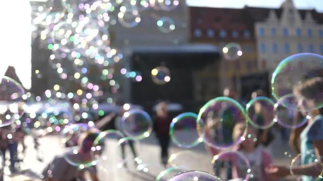 Huge amount of soap bubbles busker fly entertaining a city center tourists people walking in Wroclaw Poland