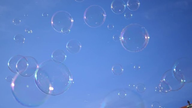 Huge amount of soap bubbles fly on a blue sky background in slow motion