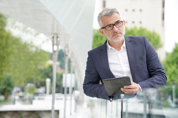 Fototapeta premium Businessman in city street connected with digital tablet