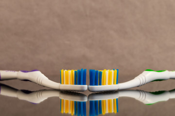 Two toothbrushes with a bristle of artificial fibers of different colors with reflection in the...