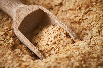Closeup of nutritional brewers yeast flakes with wooden scoop