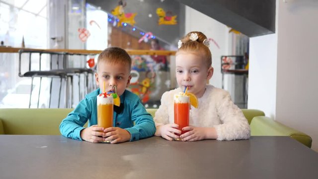 Milkshake cocktail - children in cafe, cute little girl and boy drinking from straw