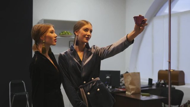 Cute young model girls taking selfie pictures via phone behind the scenes