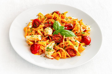 wide noodles with tomato sauce, calamari, and cherry tomatoes decorated with parsley and basil leafs 