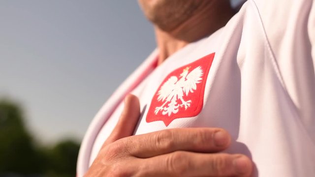 Polish Football Fan Proud to Be Part of the Match Keeping His Hand on the Heart Near Polish National Symbol.