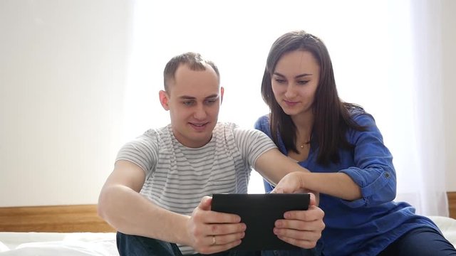 Young family couple watch tablet computer view their travel photo pictures