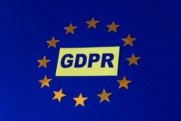 General Data Protection Regulation concept. Letters GDPR on yellow sticker and European Union flag with gold stars on a blue background. Selective focus