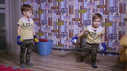 Twin kids boys have fun enjoy playing fighting with boxing gloves at home