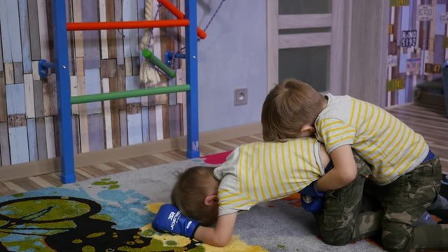 Twin kids boys have fun enjoy playing fighting with boxing gloves at home