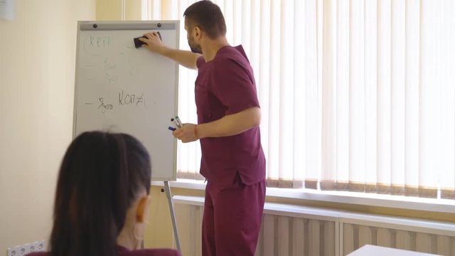 Medical Symposium. A Male Doctor Writes On The Board A Medical Formula And Discusses The Problems Of Medicine With Several Doctors. Medical Lecture. 4K