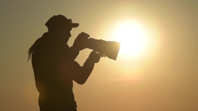 Outdoor Photographer Equipped with Large Telephoto Lens in the Remote Location During Scenic Sunset.