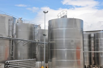 Large steel tanks for wine maturation, with cloudy sky background, winery modern equipment, closeup, front view