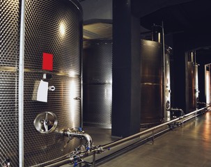 Large fermenters steel tanks stand in a row, wine modern factory equipment