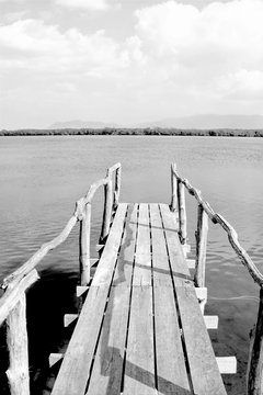 Old wooden bridge or pier to the sea in black and white, Thailand.