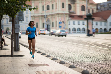 Young fitness woman running on sidewalk