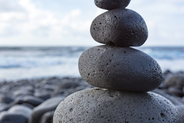 Detail of balanced stacked stones or pebbles on a beach with the horizon in the background.