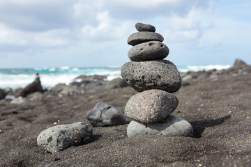 Balanced stacked stones or pebbles on a black sand beach.