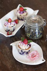 Фруктовые пирожные с клубникой и стеклянной банкой черного чая на деревянном столе
