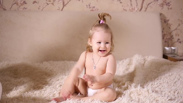 Little cute baby toddler girl play at home have fun sitting on bed slow motion