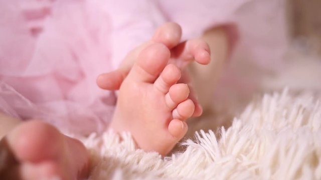 Little baby toddler fingers touching strocking her leg foot toes closeup slow motion