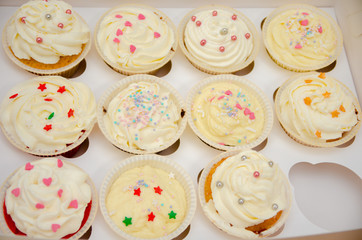 muffins with cream and sprinkling in the form of stars and beads, muffins in paper, ready delicious cakes