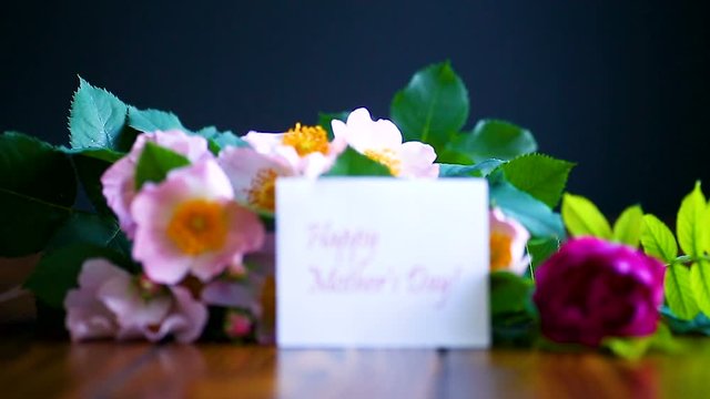 beautiful blooming roses and a greeting card for the mother