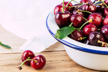 cherries in a white enamel bowl on a wooden table, fresh cherry, seasonal berries, cherry, ripe berries