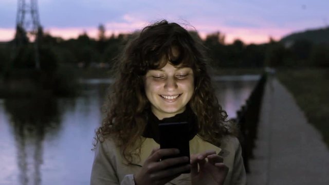 Young Woman Smiling Using Her Smartphone.