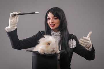 Beautiful woman magician with rabbit in hat