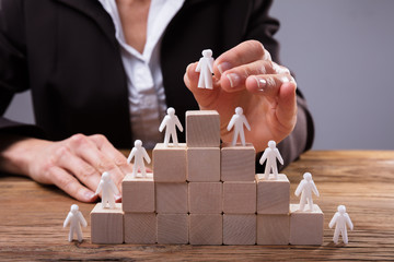 Close-up Of A Businessperson Placing Human Figures